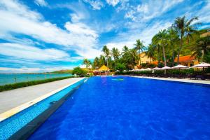 a large blue swimming pool next to the ocean at Hon Rom Central Beach Resort in Mui Ne