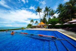 a man in a swimming pool next to the ocean at Hon Rom Central Beach Resort in Mui Ne