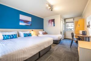 um quarto de hotel com duas camas e uma secretária em Nightcap at Riverside Hotel em Launceston