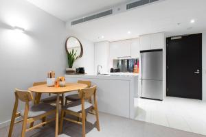 a kitchen with a table and chairs and a refrigerator at Boutique Abode 313 in Melbourne