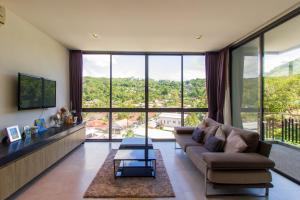 Una sala de estar con un sofá y grandes ventanales. en Icon Park Apartments - Kamala Beach, en Kamala Beach
