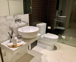 Baño blanco con lavabo y aseo en Boutique Abode 314 en Melbourne