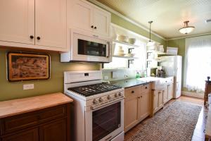 a kitchen with white cabinets and a stove top oven at Das Meyer Haus - Luxe Victorian in Schulenburg