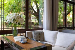 a living room with a couch and a table with a vase of flowers at Jun Bo Xuan Boutique Hotel in Lijiang