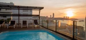 a swimming pool on the roof of a building with the sunset at Inn House- SHA Extra Plus in Pattaya Central