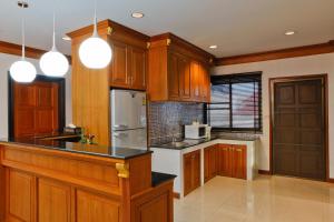 a kitchen with wooden cabinets and a white refrigerator at Inn House- SHA Extra Plus in Pattaya