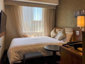 a hotel room with a bed and a window at HOTEL UNIZO Nagoya Ekimae in Nagoya
