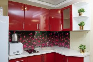 ケメロヴォにある1-к квартира 9 января, 6の赤いキャビネットとピンクの花が壁に飾られたキッチン