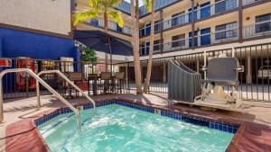 einem Pool mit einem Stuhl und einem Gebäude in der Unterkunft Best Western Airport Plaza Inn Hotel - Los Angeles LAX in Los Angeles