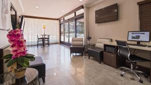 a living room with a tv and a desk and chairs at Best Western Hollywood Plaza Inn Hotel - Hollywood Walk of Fame LA in Los Angeles