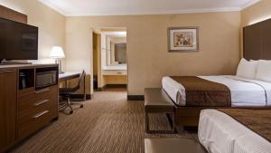 a hotel room with a bed and a desk with a television at Best Western Hollywood Plaza Inn Hotel - Hollywood Walk of Fame LA in Los Angeles