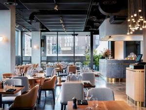 a restaurant with tables and chairs and a bar at Novotel Melbourne South Wharf in Melbourne