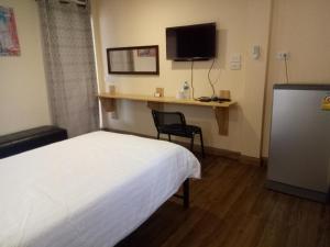 a bedroom with a bed and a desk with a television at Little Guest House Hotel in Chiang Mai