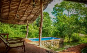 a patio with a swimming pool and a chair at Wild Wadi Wilpattu - Villas with private Plunge Pools in Wilpattu