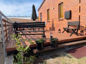 una terraza de madera con 2 bancos y una sombrilla en Peter Allen Motor Inn, en Tenterfield