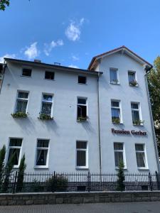 a white building with windows and a fence at Pension Gerber in Erfurt