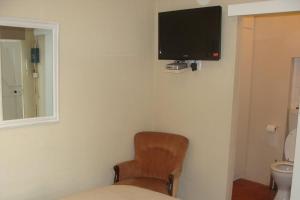 um quarto com uma cadeira e uma televisão na parede em Coweys Corner em Durban