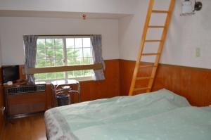 1 dormitorio con escalera, cama y ventana en Annex Aburaya, en Iiyama