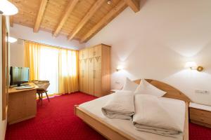 um quarto com uma cama, uma secretária e uma televisão em Hotel Fernblick em San Valentino alla Muta