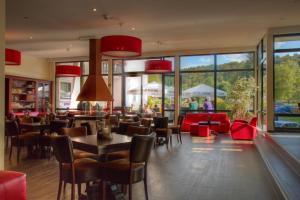 um restaurante com cadeiras vermelhas, mesas e janelas em Hotel Winterberg Resort em Winterberg