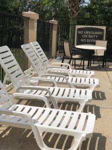 a row of white lawn chairs with a no lifeguard on duty sign at WeStay Suites - Covington/Mandeville in Covington