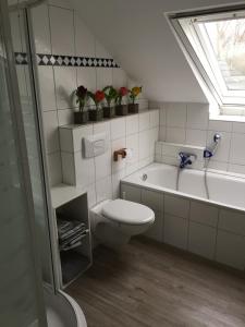 a white bathroom with a toilet and a bath tub at Ferienwohnung Kolb in Issum
