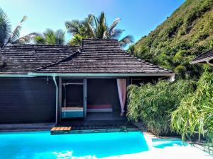 a house with a swimming pool next to a hill at Pool Mountain Moorea in Moorea