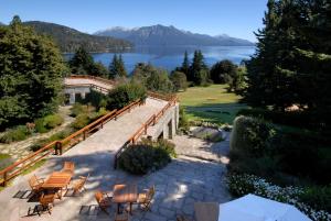 a patio with tables and chairs and a view of a lake at Hotel Tunquelén in San Carlos de Bariloche