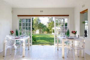 un comedor blanco con mesas blancas y sillas blancas en Bloomestate Swellendam en Swellendam