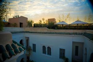 ein weißes Gebäude mit Sonnenuntergang im Hintergrund in der Unterkunft Riad Idra in Marrakesch