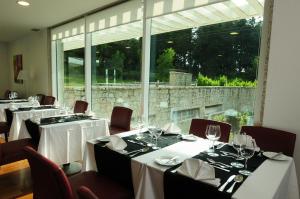 uma sala de jantar com mesas e cadeiras e uma grande janela em INATEL Vila Ruiva em Vila Ruiva