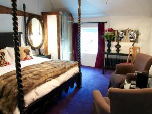 a bedroom with a canopy bed and a chair at The Black Horse Fulmer in Fulmer