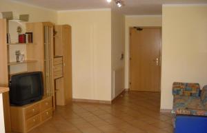 a living room with a tv on a dresser and a couch at Appartments Am Wiesenrand in Nova Ponente