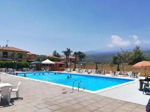 ein Schwimmbad mit Menschen in einem Resort in der Unterkunft Villa Achillea - villetta con jacuzzi privata e piscina condominiale in Mascali