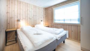 um quarto com uma cama com lençóis brancos e uma janela em Geilolia Hyttetun em Geilo