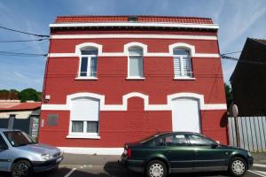 un edificio rojo con un coche verde aparcado delante de él en T2 de charme N3 Valenciennes Netflix, Wifi,, en Aulnoy