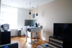 ein Wohnzimmer mit einem Schreibtisch und einem TV in der Unterkunft T2 de charme N3 Valenciennes Netflix, Wifi, in Aulnoy