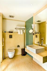 a bathroom with a sink and a toilet and a mirror at Flora Airport Hotel and Convention Centre Kochi in Nedumbassery