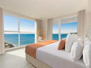 a hotel room with a large bed and a large window at Amàre Beach Hotel Ibiza Adults Only in San Antonio Bay