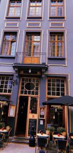 un bâtiment violet avec des tables et des chaises devant lui dans l'établissement Gran Hotel De Passage, à Bruges