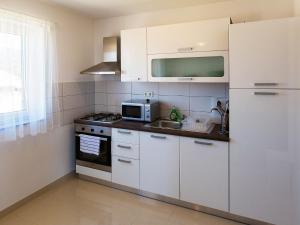 eine Küche mit weißen Schränken und einer Spüle und einer Mikrowelle in der Unterkunft Apartment Leko-4 by Interhome in Novi Vinodolski + 29 Fotos