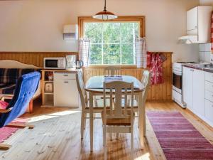 a kitchen with a table and chairs and a window at Holiday Home Naurulokki 4 by Interhome in Strandby