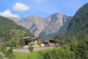 una casa en una colina con montañas en el fondo en Gasthof Bundschen, en Sarentino