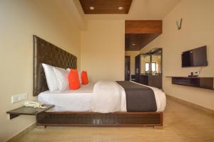 1 dormitorio con 1 cama grande con almohadas de color naranja en Nakshatra Resort en Kunihar