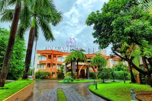 a hotel with palm trees in front of it at Flora Airport Hotel and Convention Centre Kochi in Nedumbassery