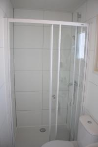uma casa de banho branca com um chuveiro e um WC. em Chalet Charlee em IJmuiden