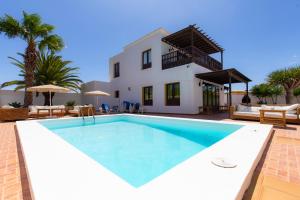 a villa with a swimming pool in front of a house at Villas Reina in Costa Teguise