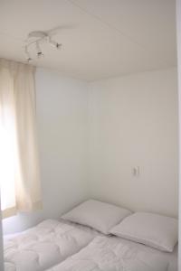 a white bedroom with a bed and a window at Chalet Charlee in IJmuiden