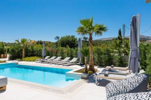 una piscina con tumbonas y una palmera en Vasilios Villa, Luxury Escape, By ThinkVilla en Loutra