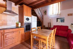 eine Küche mit einem Holztisch und einer roten Couch in der Unterkunft Home2Book Stunning Rustic House El Pinar & WiFi in El Pinar del Hierro